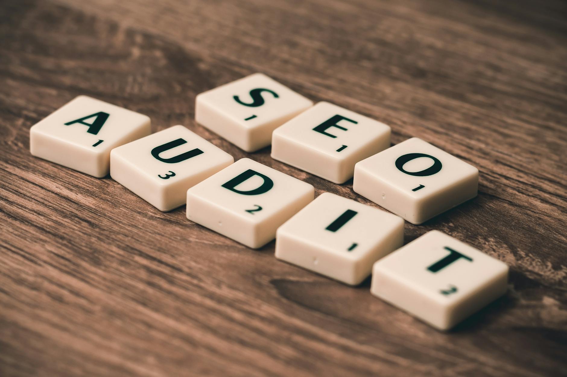 Kafelki Scrabble układające się w napis SEO Audit na drewnianym stole