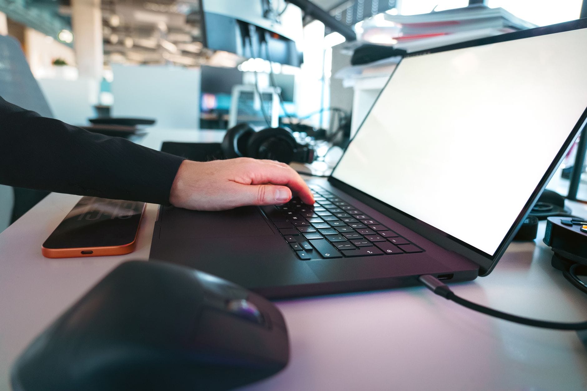Dłoń pisząca na klawiaturze laptopa w nowoczesnym biurze